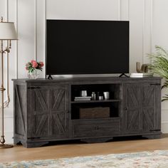 an entertainment center with a large flat screen tv on it's stand in front of a white wall