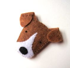 a brown and white dog brooch sitting on top of a white table next to a wall