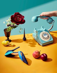 a person is using an old fashioned telephone on a table with other items around it