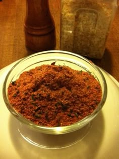 a glass bowl filled with spices on top of a white plate