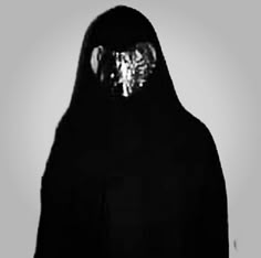 a woman wearing a black veil and holding a cell phone in her hand with the light shining on her face