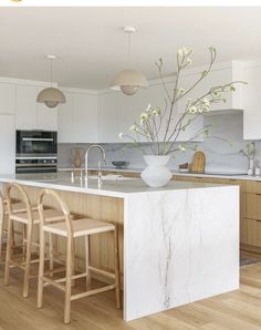 a large kitchen island with stools next to it and a vase filled with flowers