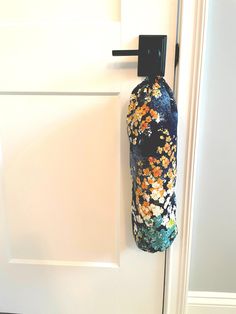 a bottle hanging on a door handle next to a white door with a floral design