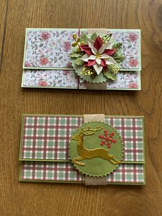 two christmas cards on a table, one with a deer and the other with poinsettis