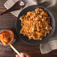 a person holding a spoon in front of a plate of food on a wooden table