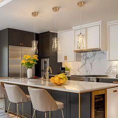 a large kitchen with marble counter tops and gold accents on the island, along with white chairs