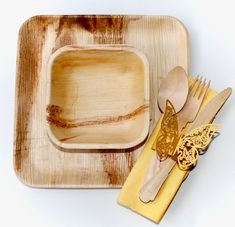 a wooden plate with utensils on it next to a yellow napkin and fork