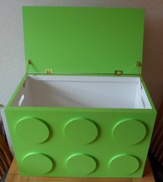 a green box with four circles on the lid and two sides, sitting on top of a wooden table