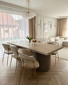 a dining room table with chairs and a couch in the backround next to it