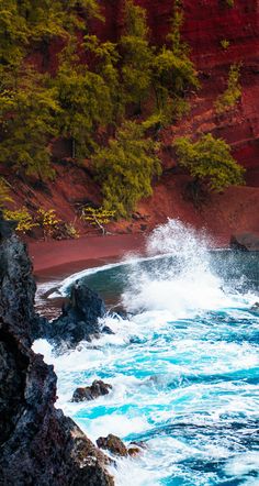 the waves are crashing against the red cliffs