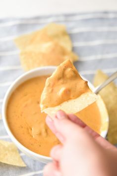 a person dipping tortilla chips into a bowl