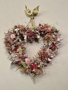 a floral wreath hangs on the wall with a gold bow hanging from it's side