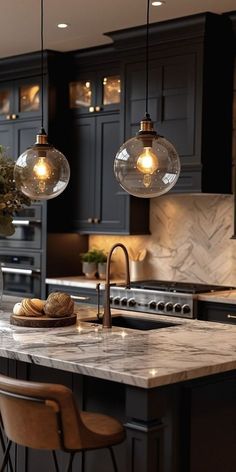 a kitchen with marble counter tops and two hanging lights above the island, along with wooden bar stools