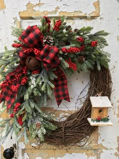 a christmas wreath hanging on the side of a door with red berries and pine cones