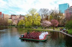 a boat filled with lots of white jugs floating on top of a lake next to tall buildings