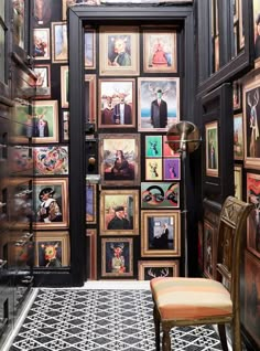 a room with many pictures on the wall and a chair in front of an open door