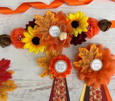 flowers and ribbons are arranged on a white wooden table with orange, yellow, and red ribbon