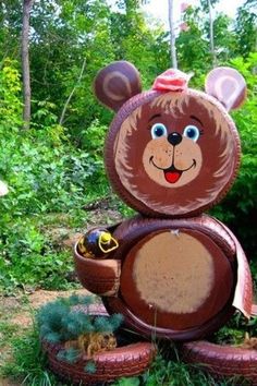 a statue of a bear holding a basket in the grass with mushrooms and trees behind it