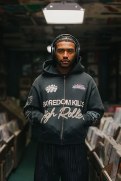 a man wearing headphones standing in a room full of records and cds with his hands on his hips