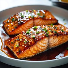 two salmon fillets on a plate with sauce