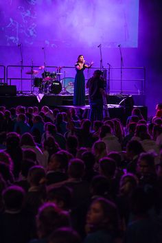 a woman standing on top of a stage in front of a large group of people