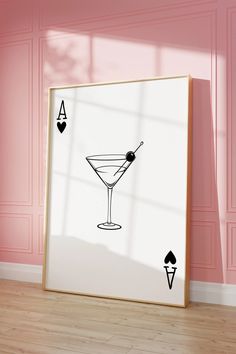 a card deck with a martini glass on the table in front of a pink wall