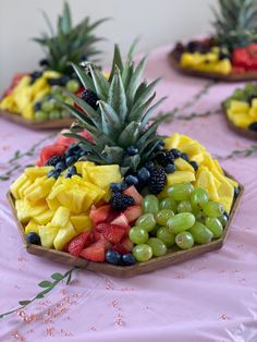 fruit tray with pineapples, grapes, and strawberries arranged in the shape of hexagon