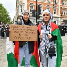 two women standing next to each other holding flags and a sign that says, freedom is never given by the greens