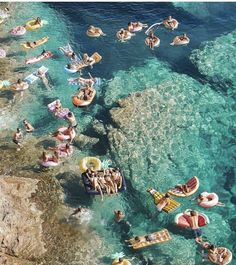 people floating on inflatable rafts near the ocean shore with clear blue water