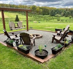 an outdoor seating area with chairs and potted plants on the ground in front of a grassy field