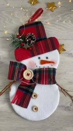 a snowman ornament with a red hat and plaid scarf