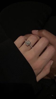 a close up of a person's hand holding an engagement ring