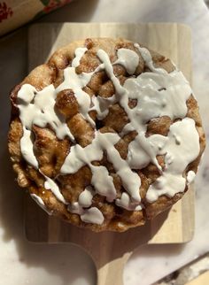 a pastry with white icing sitting on top of a wooden cutting board