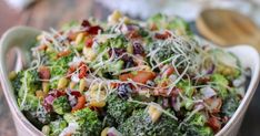 a bowl filled with broccoli, corn and other vegetables on top of a wooden table