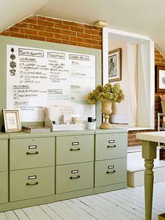 a whiteboard is on the wall next to some drawers and vases with flowers