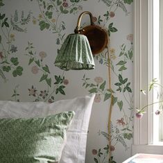 a green lamp hanging from the side of a wall next to a bed