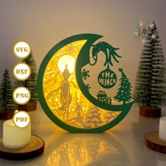 an illuminated paper cut out of the moon with trees around it and two candles in front