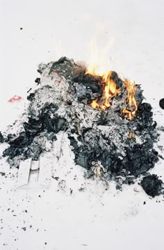 a pile of black coal sitting on top of a white floor next to a fire