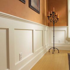 an empty room with white paneling and candles on the wall, along with two framed pictures