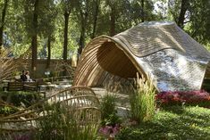 a large wooden structure sitting in the middle of a park filled with flowers and trees