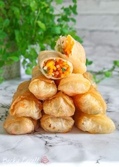 a pile of food sitting on top of a marble counter next to a potted plant