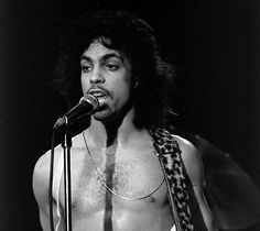 a shirtless man holding a microphone and wearing a leopard print scarf on his neck