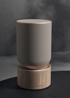 an amazon echo speaker sitting on top of a wooden stand in front of a gray background