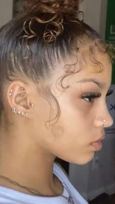 a close up of a person with hair in a bun and piercings on her ears