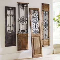 three wooden doors with wrought iron designs on the front and back, against a white wall