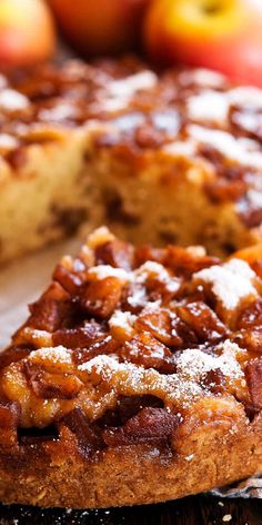 a close up of a cake on a wooden table with apples in the back ground