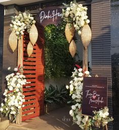 an entrance to a restaurant decorated with white flowers and greenery on the front door