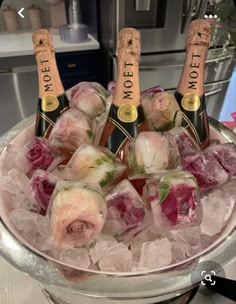 four bottles of champagne on ice in a bowl