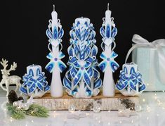 blue and white candles are sitting on a wooden board with christmas decorations around the edges