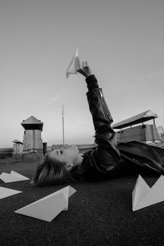 a woman laying on the ground holding a paper airplane